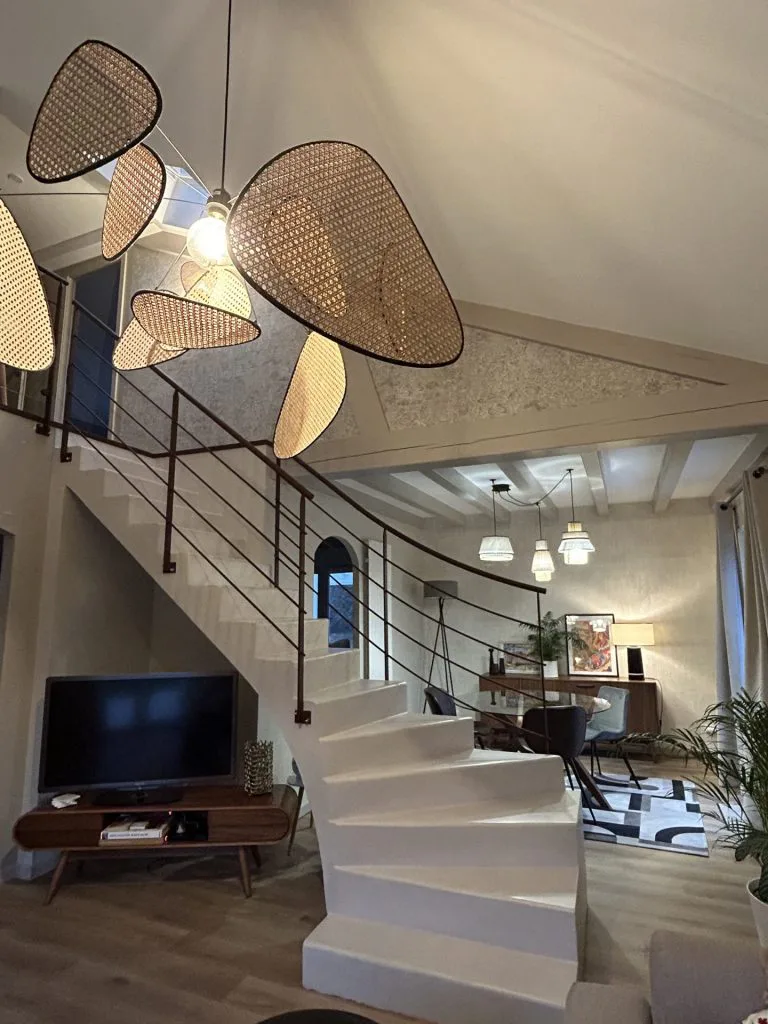 Escalier à garde-corps noir et suspension tressée devant la cheminée du salon