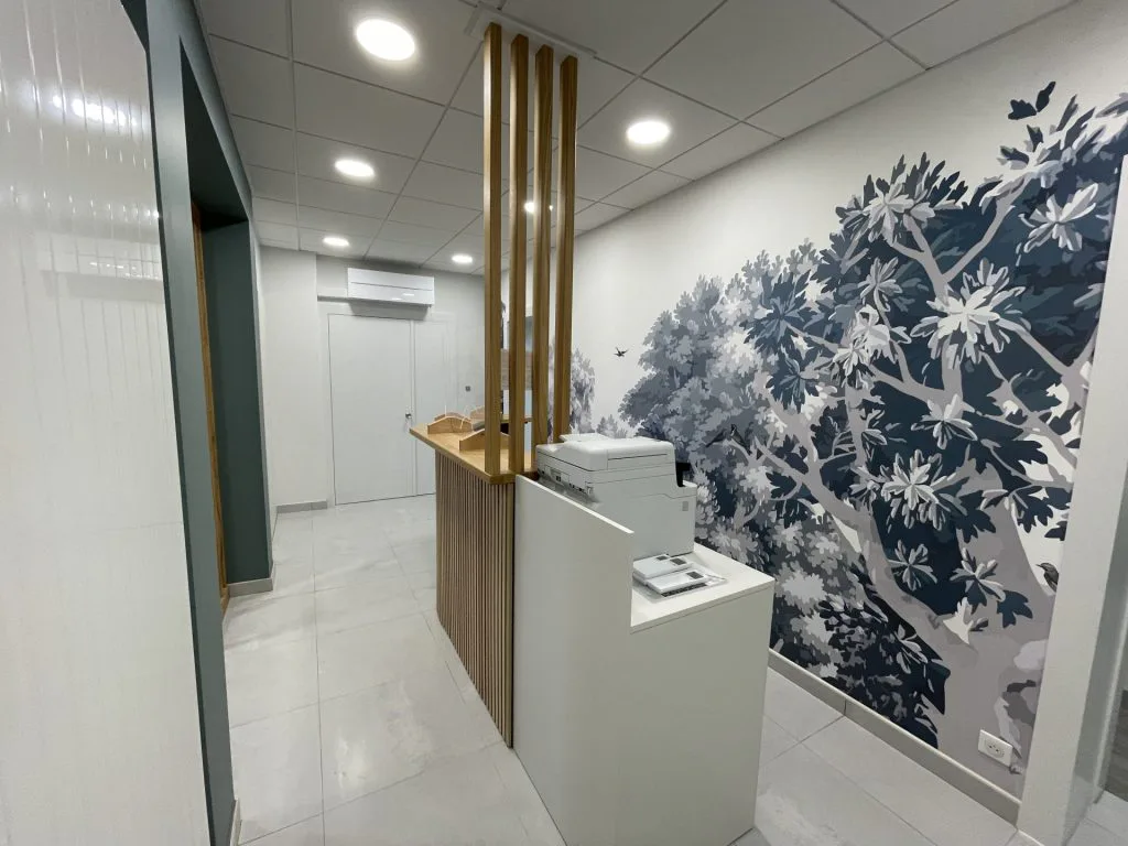 Comptoir arrondi à tasseaux de bois devant le décor forestier du nouvel accueil