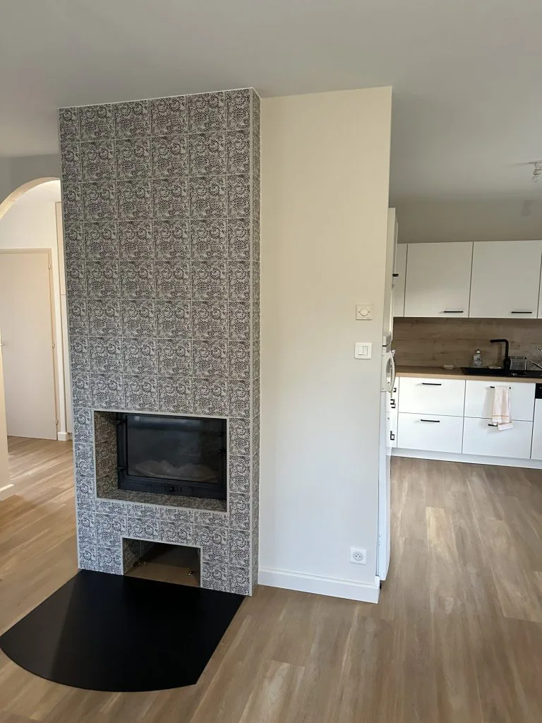 Cheminée relookée avec habillage gris texturé entre le salon et la cuisine