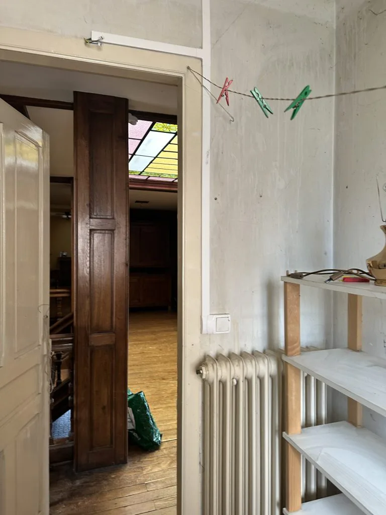 Petite pièce avant aménagement avec radiateur, étagères et porte en bois