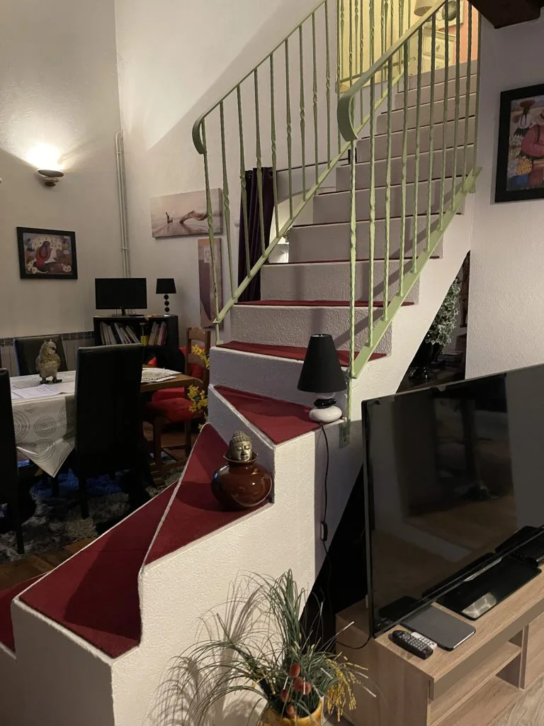 Escalier avant travaux avec marches rouges et garde-corps vert clair