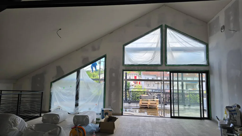 Étage du salon de thé en travaux, avec grandes baies vitrées et murs en préparation