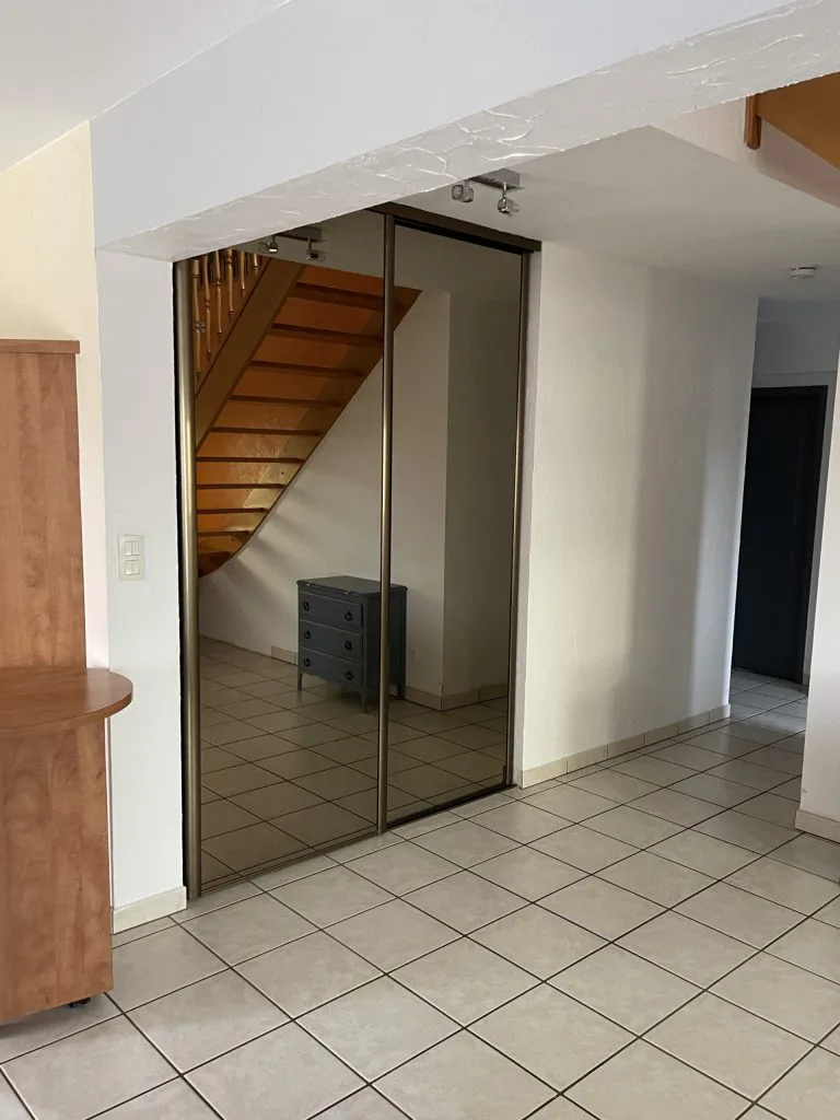 Entrée avant travaux avec placard à portes miroir au pied de l’escalier