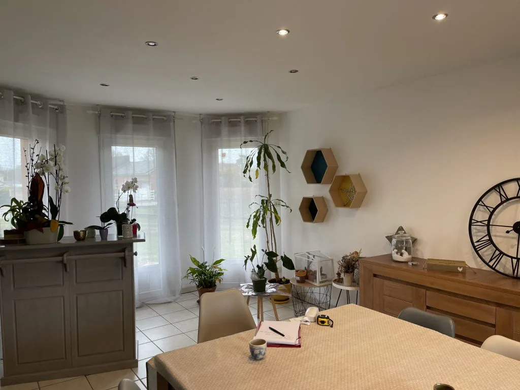 Salle à manger avant rénovation avec table, buffet en bois et plantes près des fenêtres