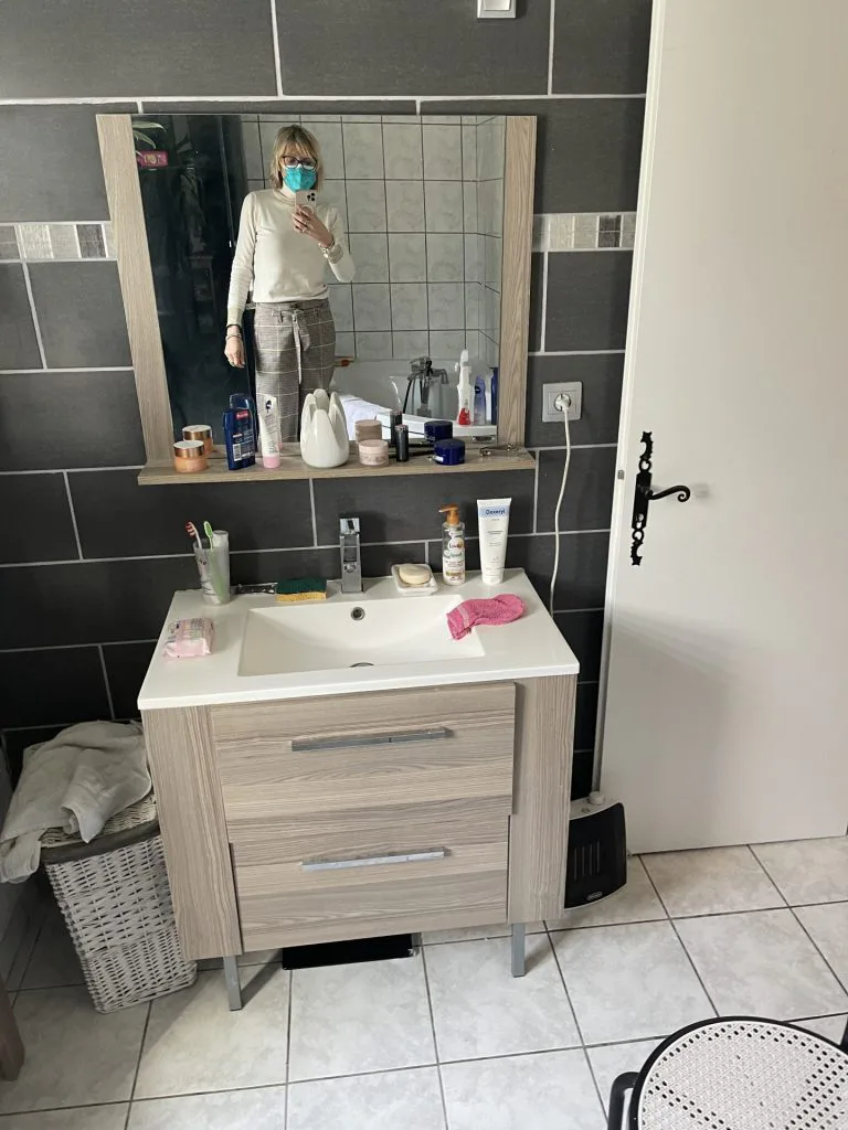 Salle de bains avant rénovation avec meuble en bois et carrelage gris foncé