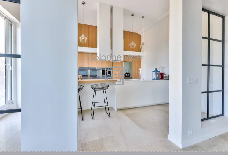 Vue du passage vers la cuisine avec verrière noire et colonne centrale
