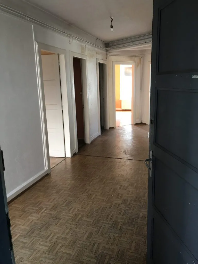 Couloir avant rénovation avec parquet ancien et plusieurs portes
