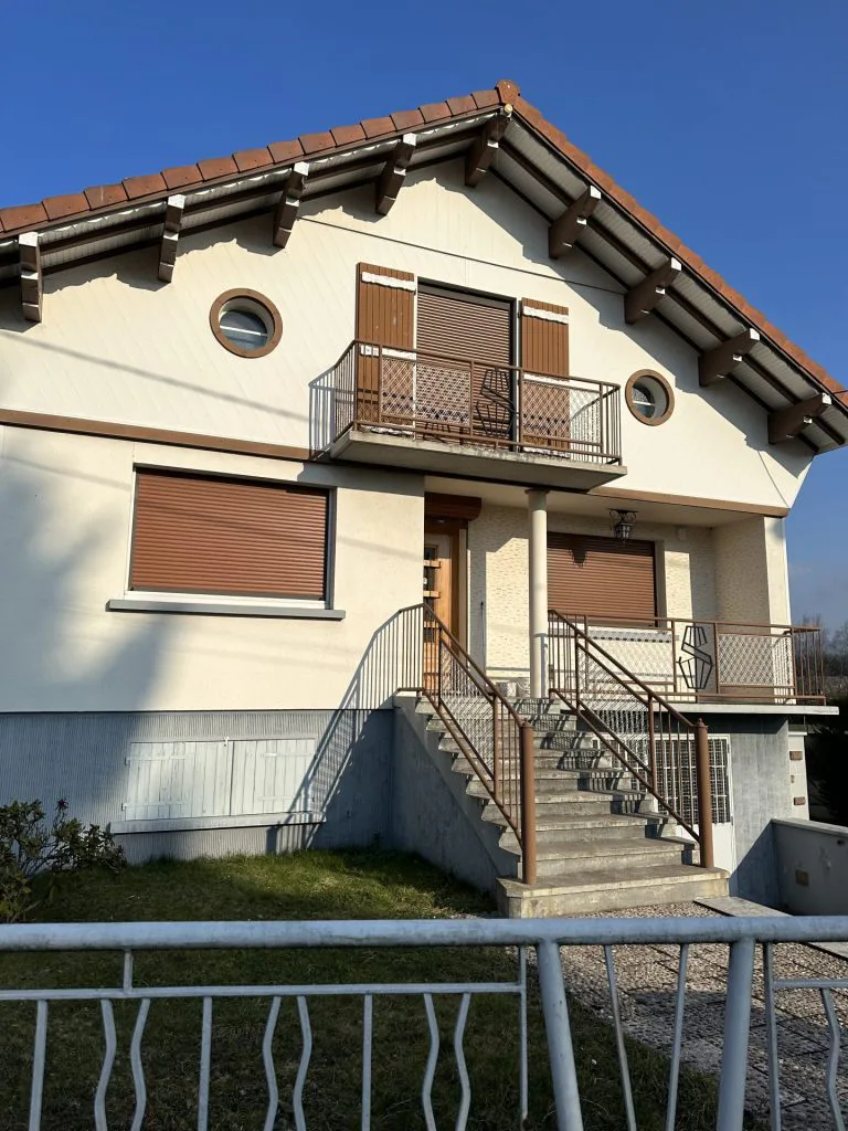 Façade de la maison avant travaux avec volets bruns, balcon et escalier extérieur