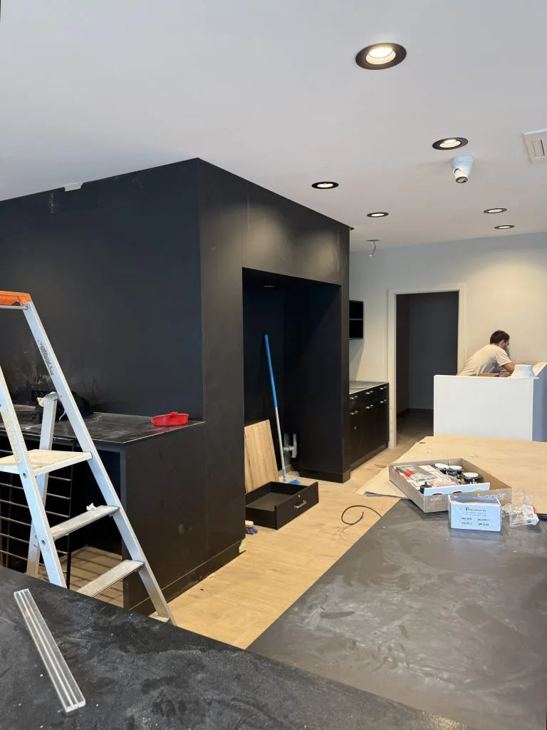 Aménagement de la boulangerie en cours avec volume central noir, escabeau et comptoir blanc