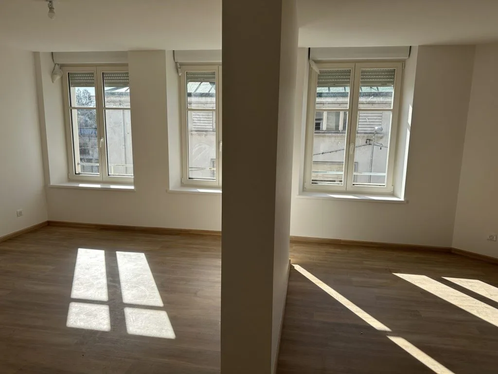 Pièce de vie après rénovation avec trois fenêtres et un poteau central