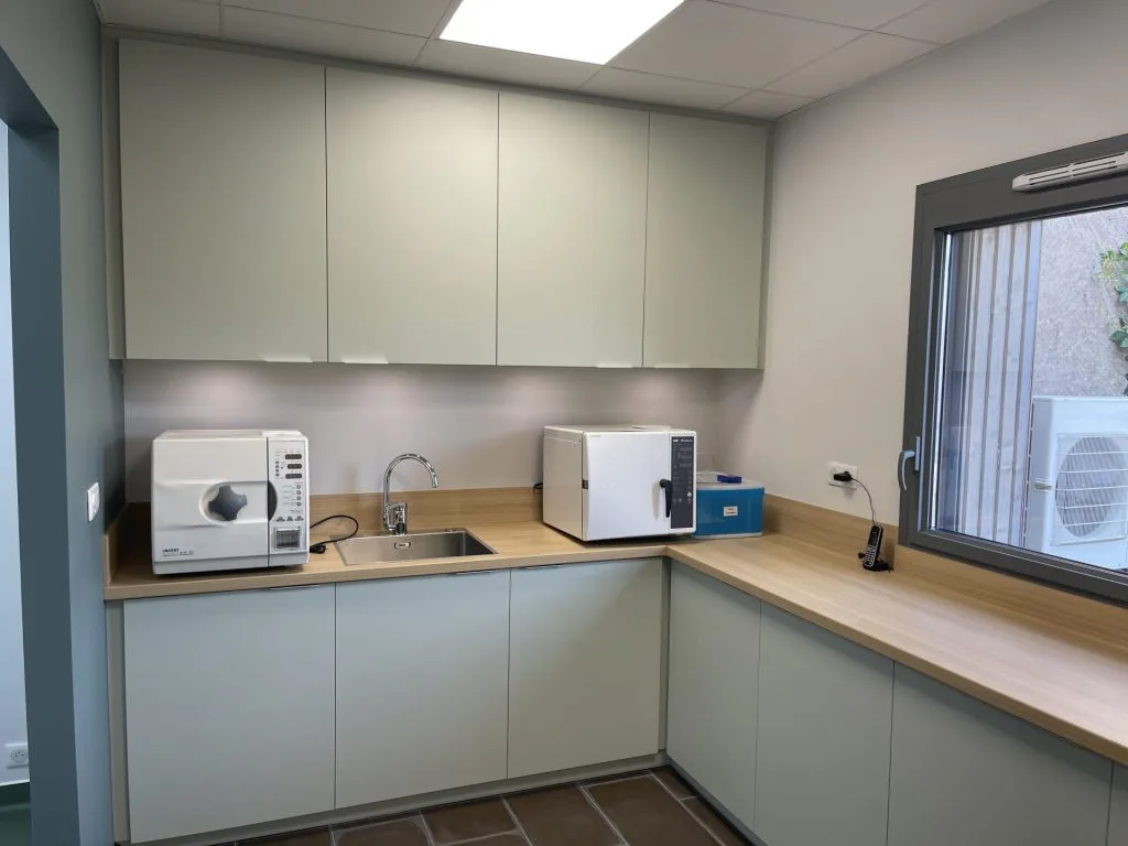 Kitchenette rénovée avec meubles gris, plan de travail en bois et four à micro-ondes