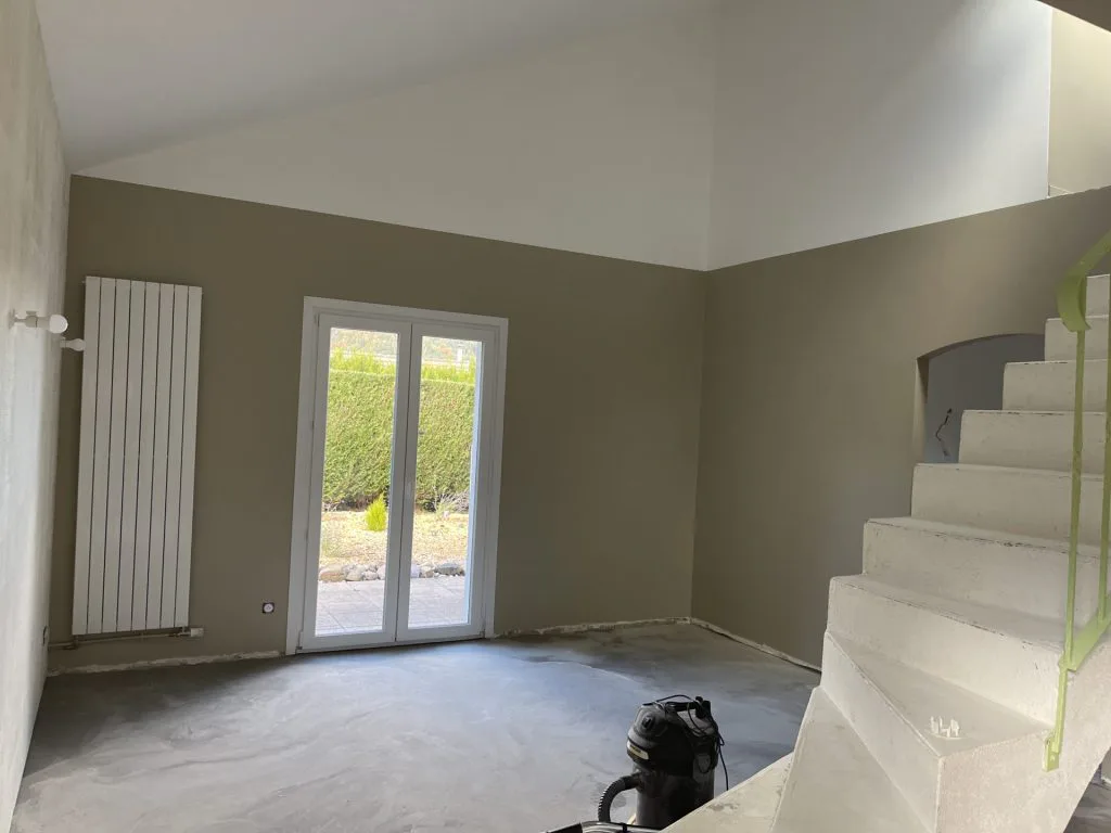 Pièce de vie pendant les travaux avec porte-fenêtre et escalier décapé