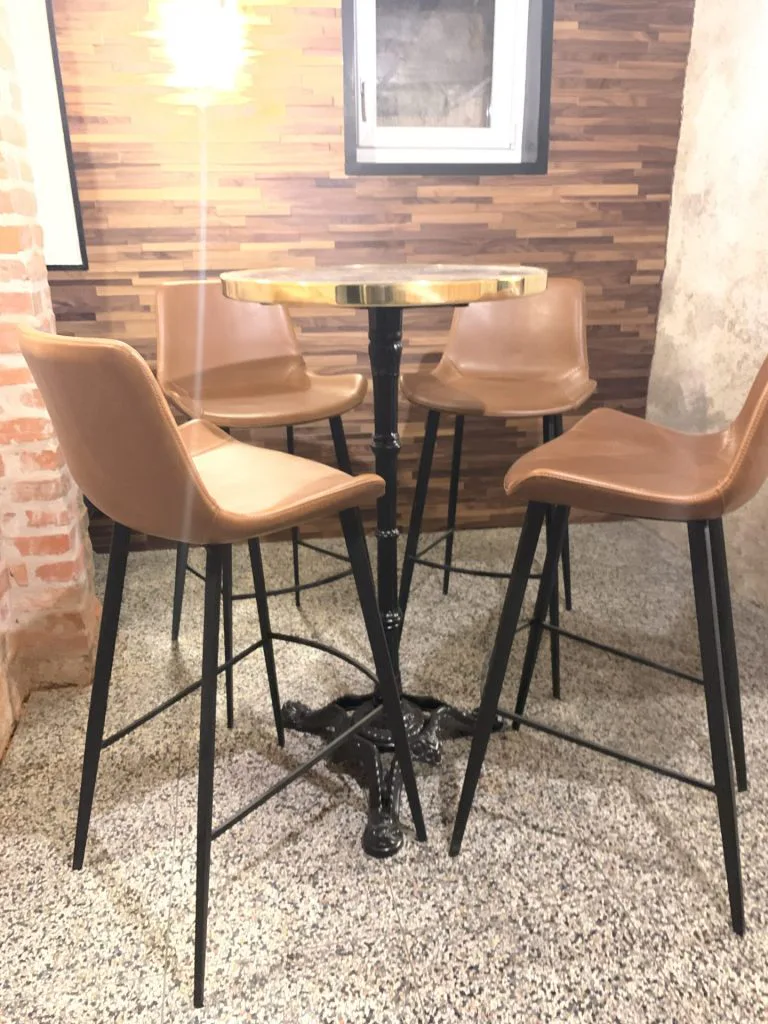 Coin dégustation aménagé avec table haute et tabourets en cuir
