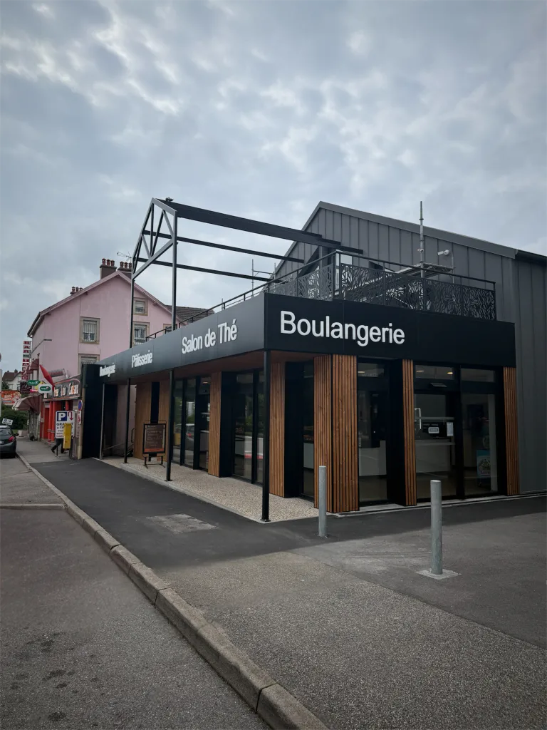 Façade de la boulangerie et du salon de thé avec enseignes noires et vitrines d’angle