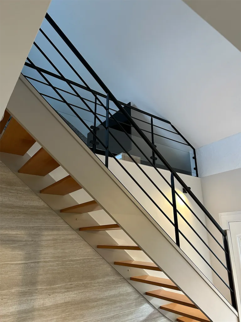 Escalier rénové avec marches en bois et garde-corps métallique noir