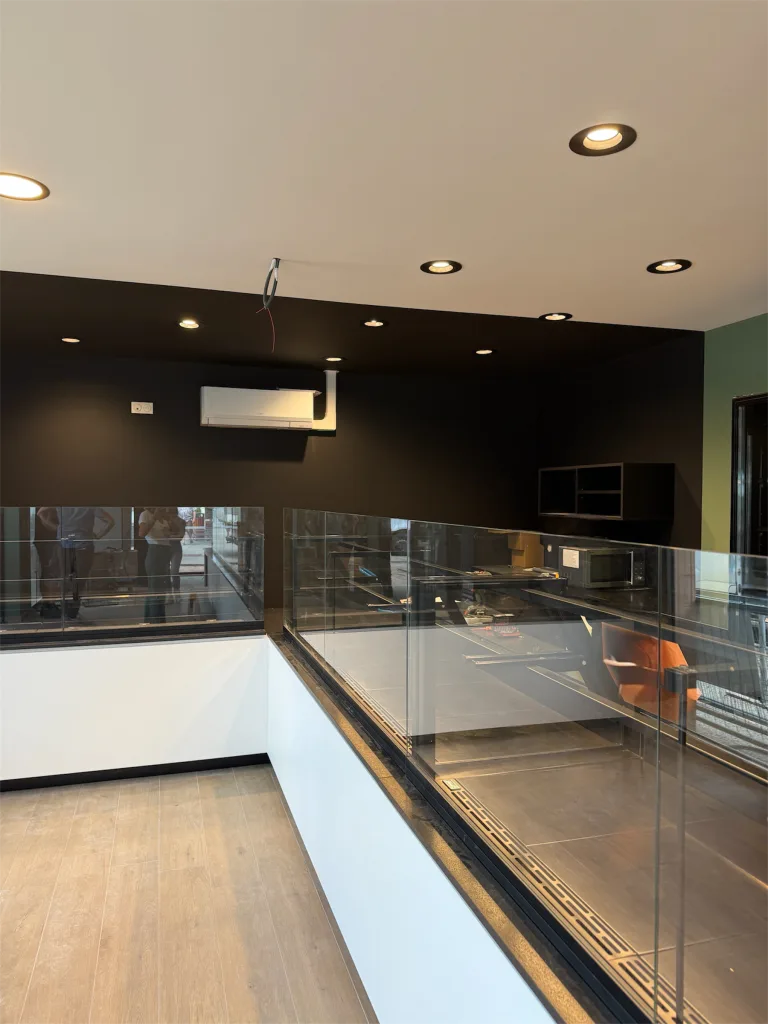 Vitrines de présentation vitrées et comptoirs blancs sous un plafond à spots