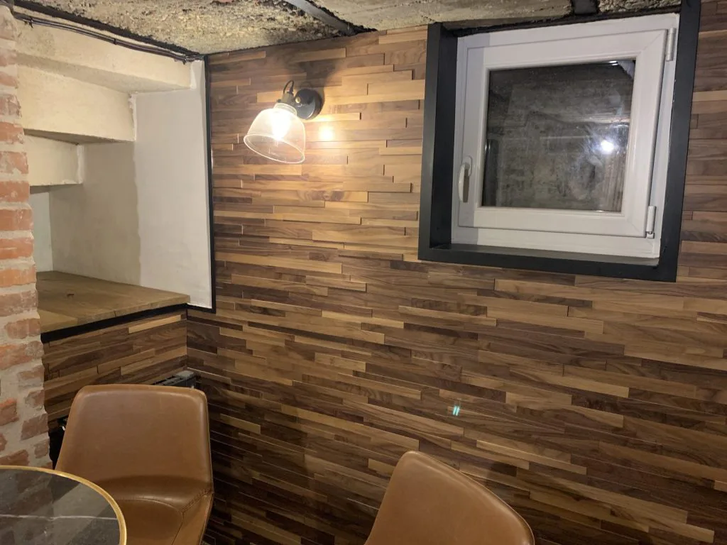 Coin dégustation avec fauteuils en cuir et mur en bois sous une applique
