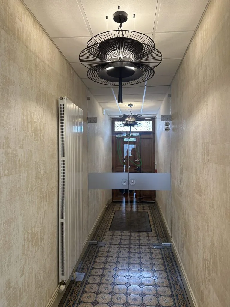 Couloir du cabinet rénové avec carrelage à motifs bleus et suspensions noires ajourées