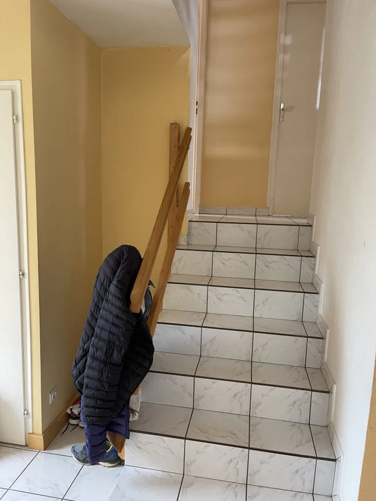 Escalier avant rénovation avec marches carrelées et rampe en bois