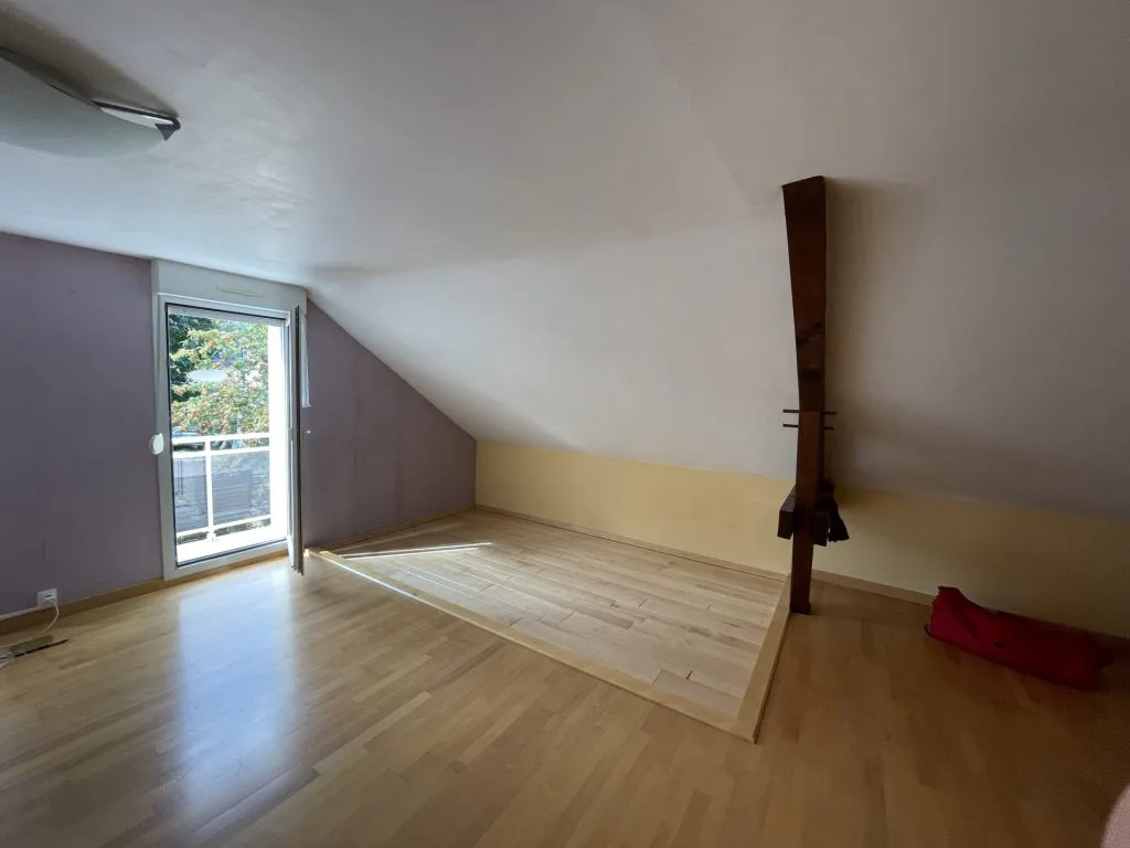 Pièce sous pente avant rénovation avec parquet et porte-fenêtre sur le balcon