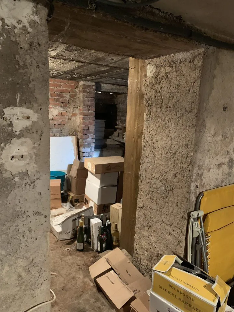 Passage de l’ancienne cave encombré de cartons avant aménagement