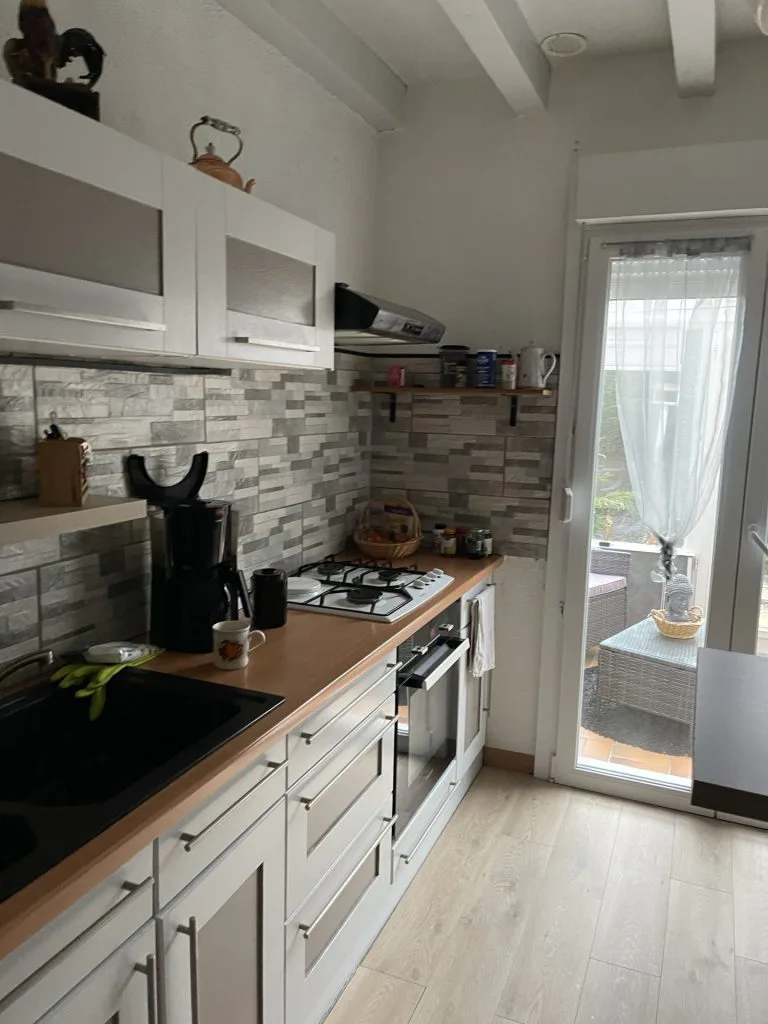 Cuisine avant rénovation avec meubles blancs et crédence mosaïque grise