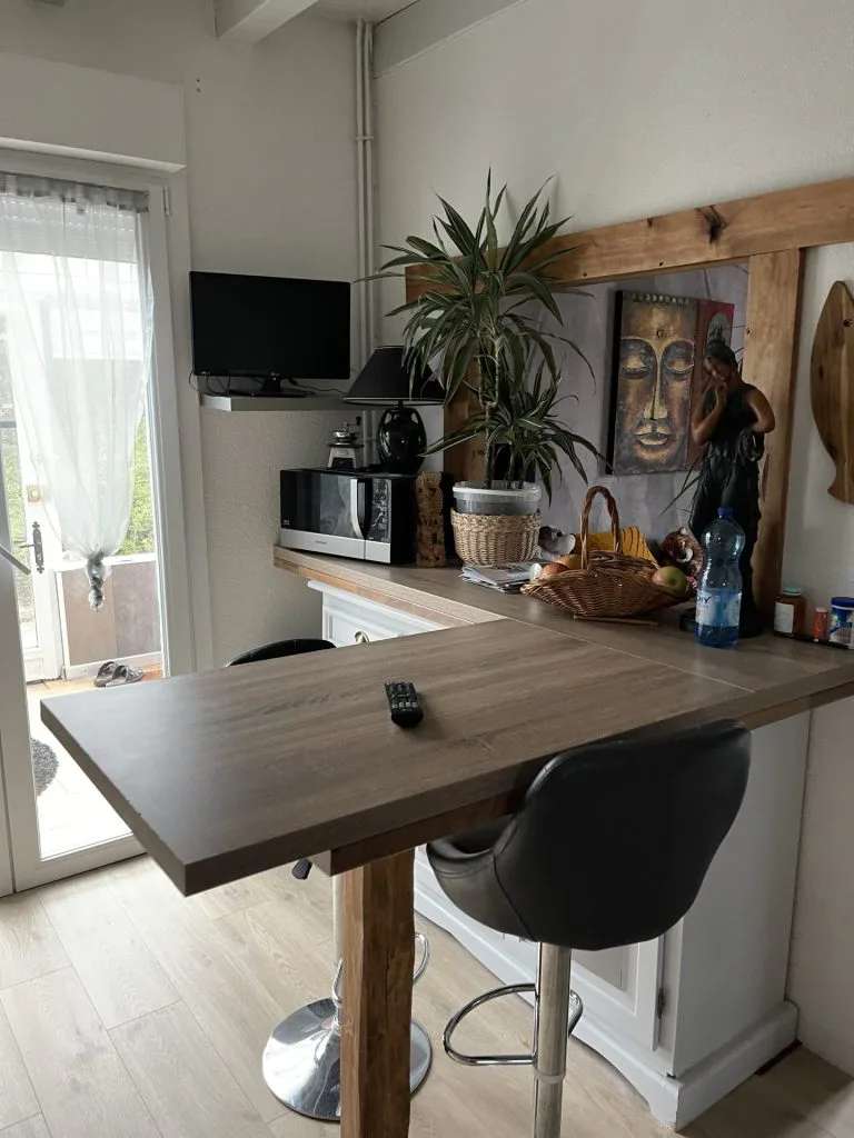 Ancien coin repas avec comptoir en bois, tabouret noir et étagères murales