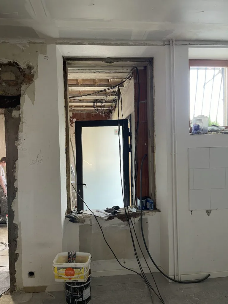 Ouverture d’une cloison pendant les travaux, avec maçonnerie apparente et matériel au sol