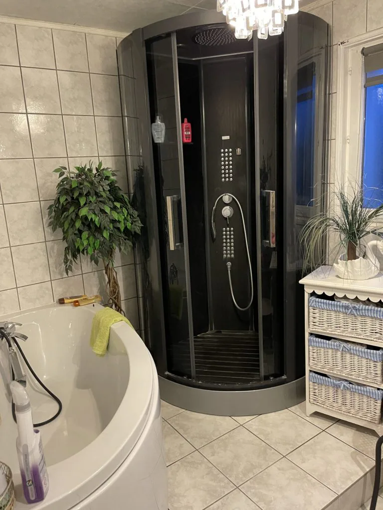 Ancienne salle de bains avec baignoire arrondie et cabine de douche noire
