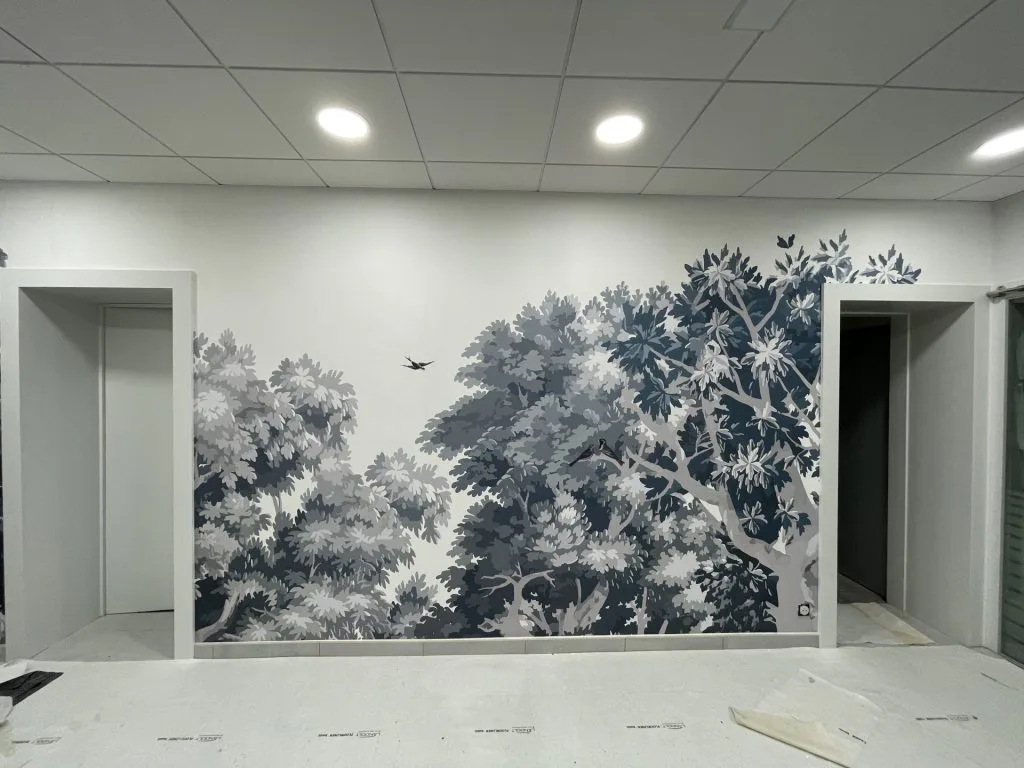 Décor mural forestier entre deux portes du cabinet dentaire rénové