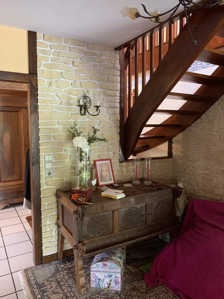 Ancienne entrée avec escalier en bois et mur imitation pierre