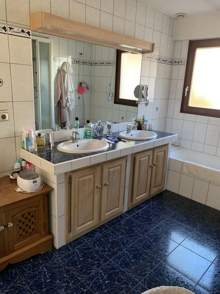 Salle de bains avant rénovation avec meuble double vasque en bois et sol bleu