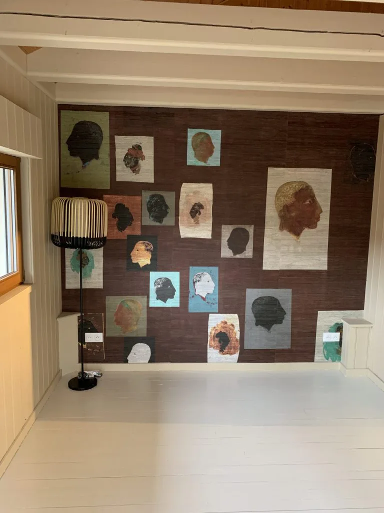 Mur de la chambre rénovée avec papier peint à portraits et lampadaire