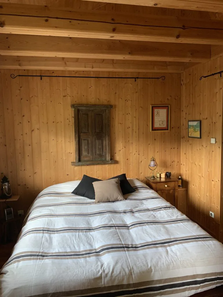 Chambre avant rénovation avec murs et poutres en bois