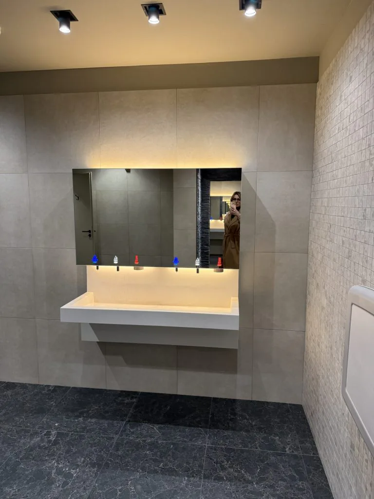 Vue d’ensemble de l’espace lavabos avec vasque suspendue, miroir et spots au plafond
